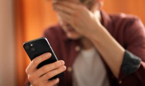 Hombre joven con gesto de preocupación mirando su teléfono móvil, simbolizando el impacto de la sobreestimulación digital en la salud mental.