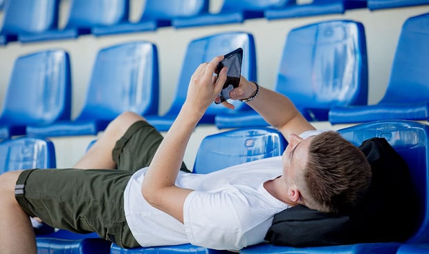 Un adolescente mirando su teléfono móvil.