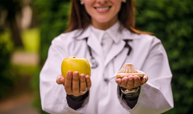 Nutricionista sujetando dos alimentos.